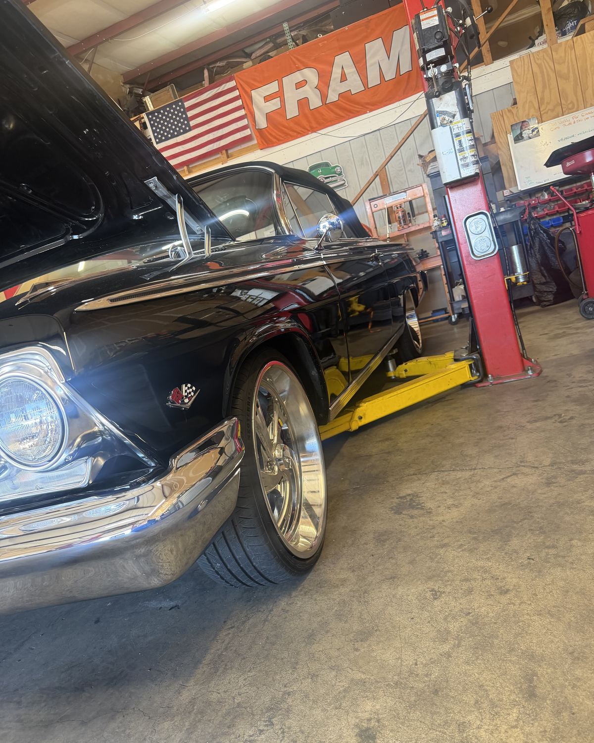 A black classic Chevrolet with chrome wheels in the bay at Ronnie’s Automotive