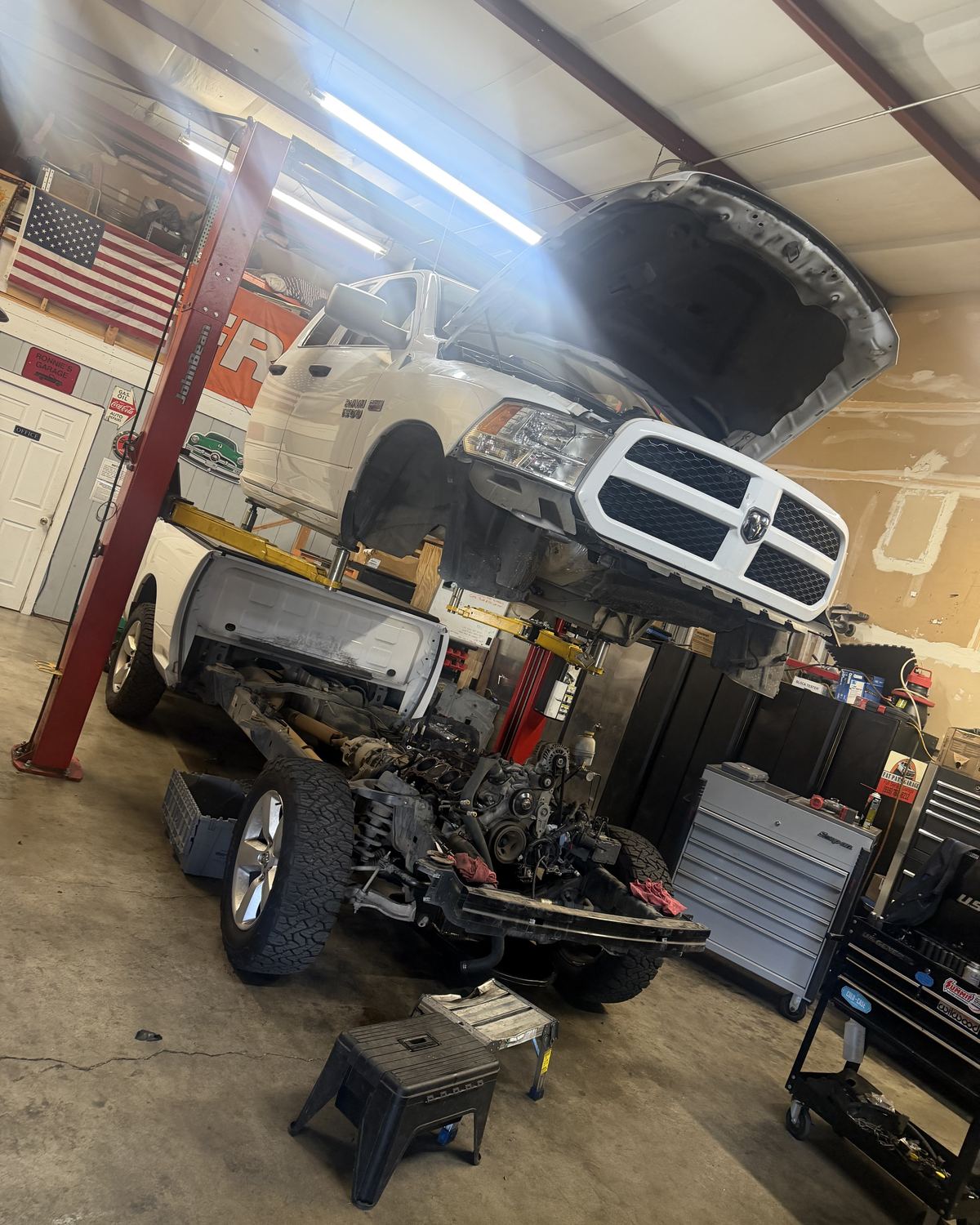 A white Ram pickup on the lift with its hood open at Ronnie’s Automotive in Sacramento
