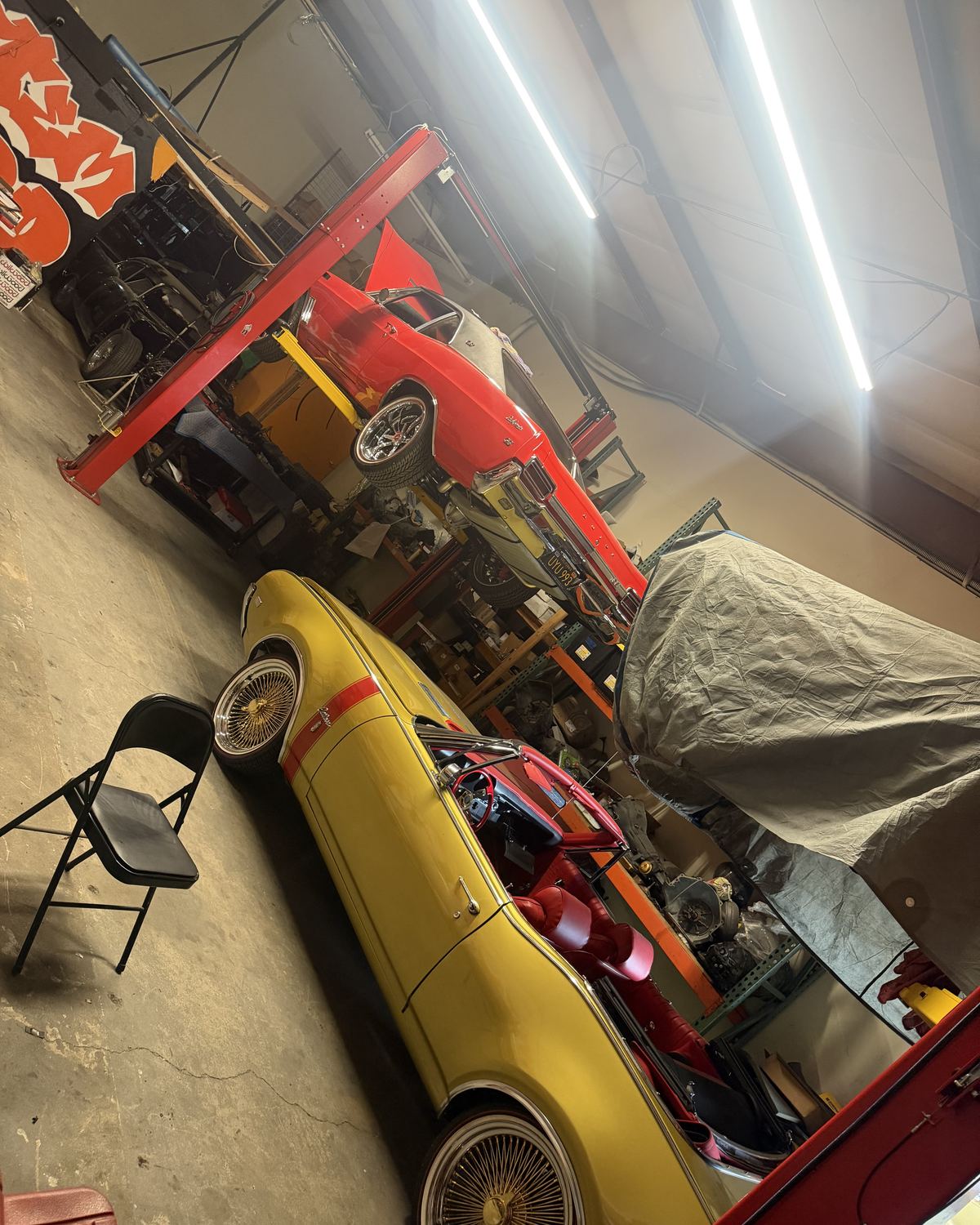 A yellow classic car with wire wheels in the shop at Ronnie’s Automotive